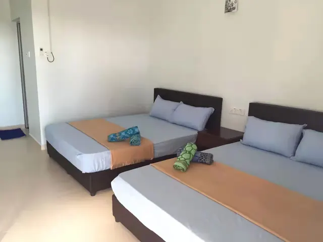 Idaman 豪华四人房内的两张大床与折叠毛巾